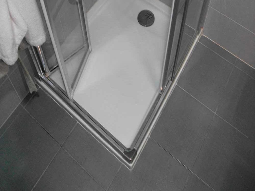 Mampara de ducha de cristal en esquina sobre el plato de ducha